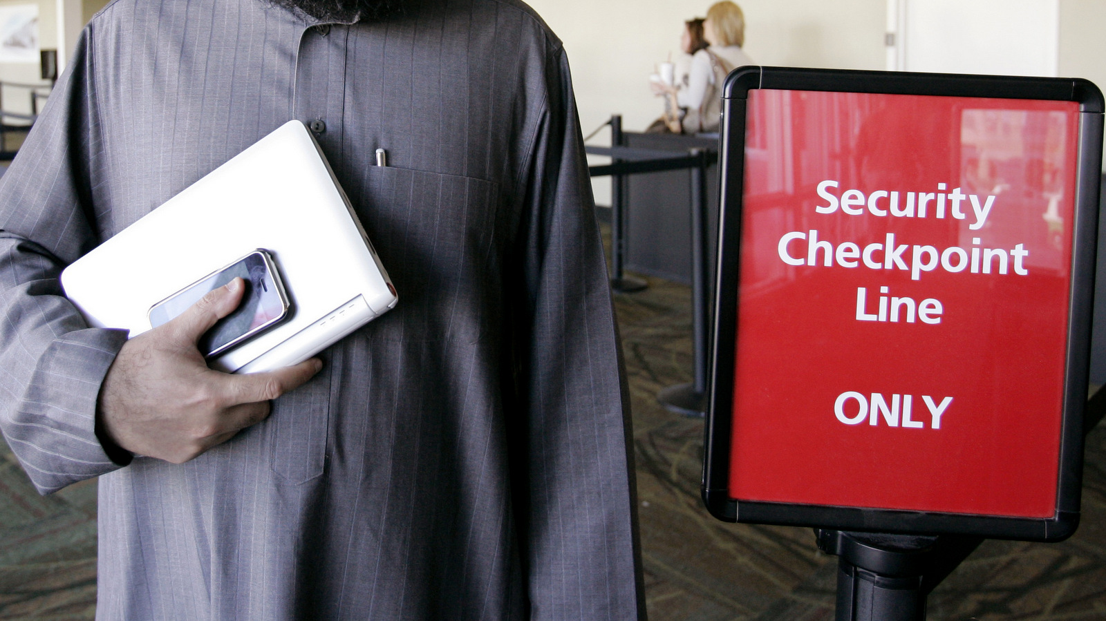 A traveler holds his laptop and iPhone that he travels with at a security checkpoint at San Jose International Airport in San Jose, Calif. (AP/Paul Sakuma)