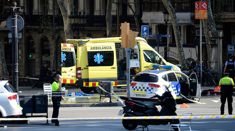 A policemen and a medical staff member stand past police cars and an ambulance Barcelona on August 17, 2017 © Josep Lago