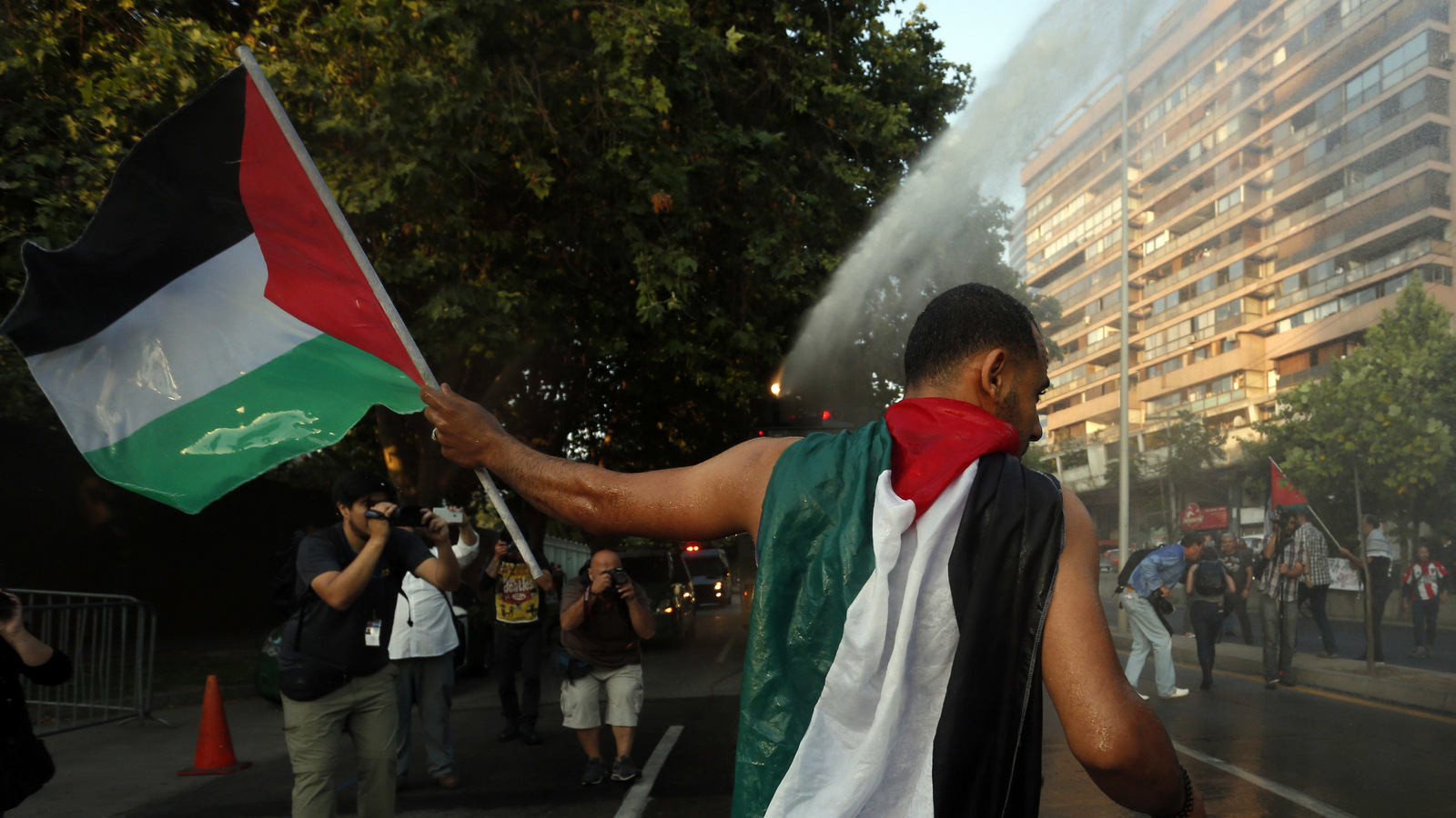 Chileans are hit with police water cannons while protesting U.S. President Donald Trump's decision to recognize Jerusalem as Israel's capital, outside the U.S. Embassy in Santiago, Chile, Dec. 11, 2017. (AP/Luis Hidalgo)