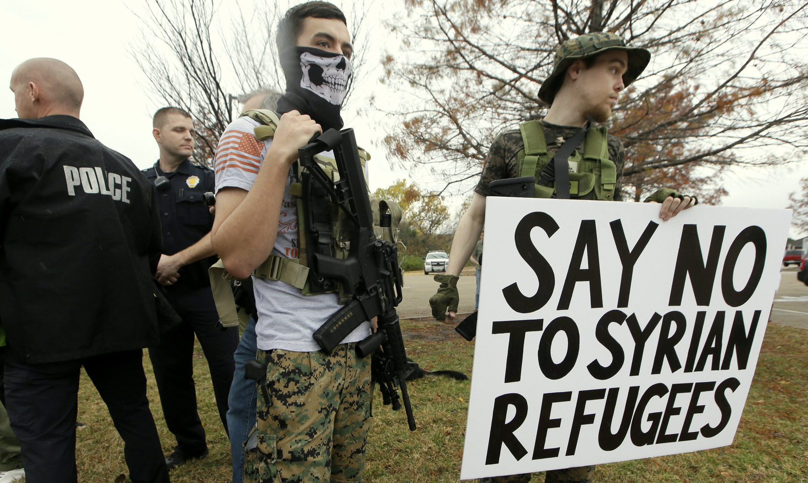 As police stand guard, armed anti-Muslim protestors, who did not want to give their names, stand across the street from a mosque during a demonstration in Richardson, Texas, on Saturday, Dec. 12, 2015. (AP Photo/LM Otero)