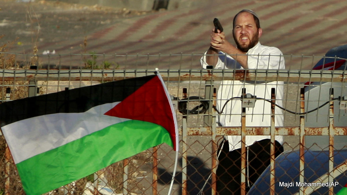 An Israeli Jewish settler shoots in the air as Palestinians protest against the Prawer Plan to resettle Israel’s Palestinian Bedouin minority from their villages in the Negev Desert, near the Israeli settlement of Bet El, north of the West Bank city of Ramallah.