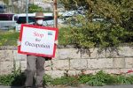 Man wears protective mask and holds sign