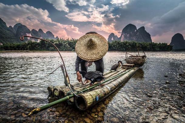 Fisherman and cormorant bird at sunset. (alexshot /Adobe Stock)