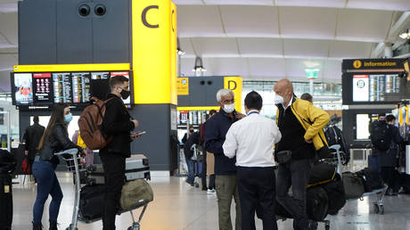 FILE PHOTO Travellers wearing a face mask stand at check-in desks at Terminal 2 of Heathrow Airport in west London on December 21, 2020 © AFP / Niklas HALLE'N