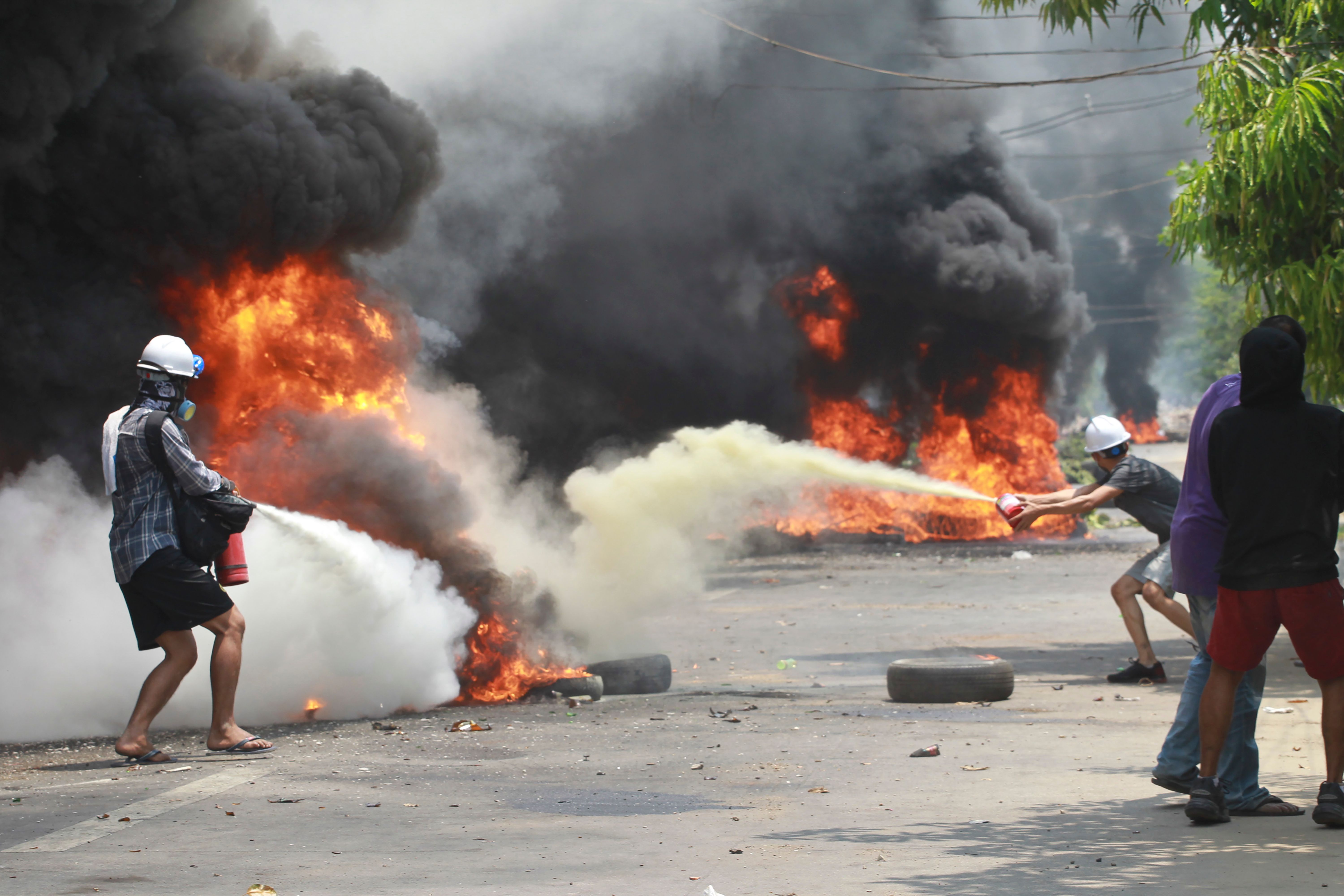 Anti-coup protesters extinguish fires during a protest in Thaketa township Yangon, Myanmar, Saturday, March 27, 2021.&nbsp;