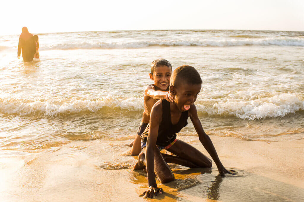 Two friends share a playful moment together on a beach near central Gaza on August 11, 2021. (Photo: Mahmoud Nasser)