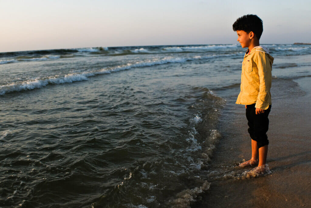 A child gleefully watches over as the sun sets on a beach during a summer day in Gaza City, Gaza, on September 30, 2021