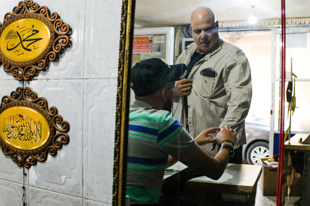 A tailor takes a client's measurements for alteration. Beit Hanoun, Gaza, September 17, 2021